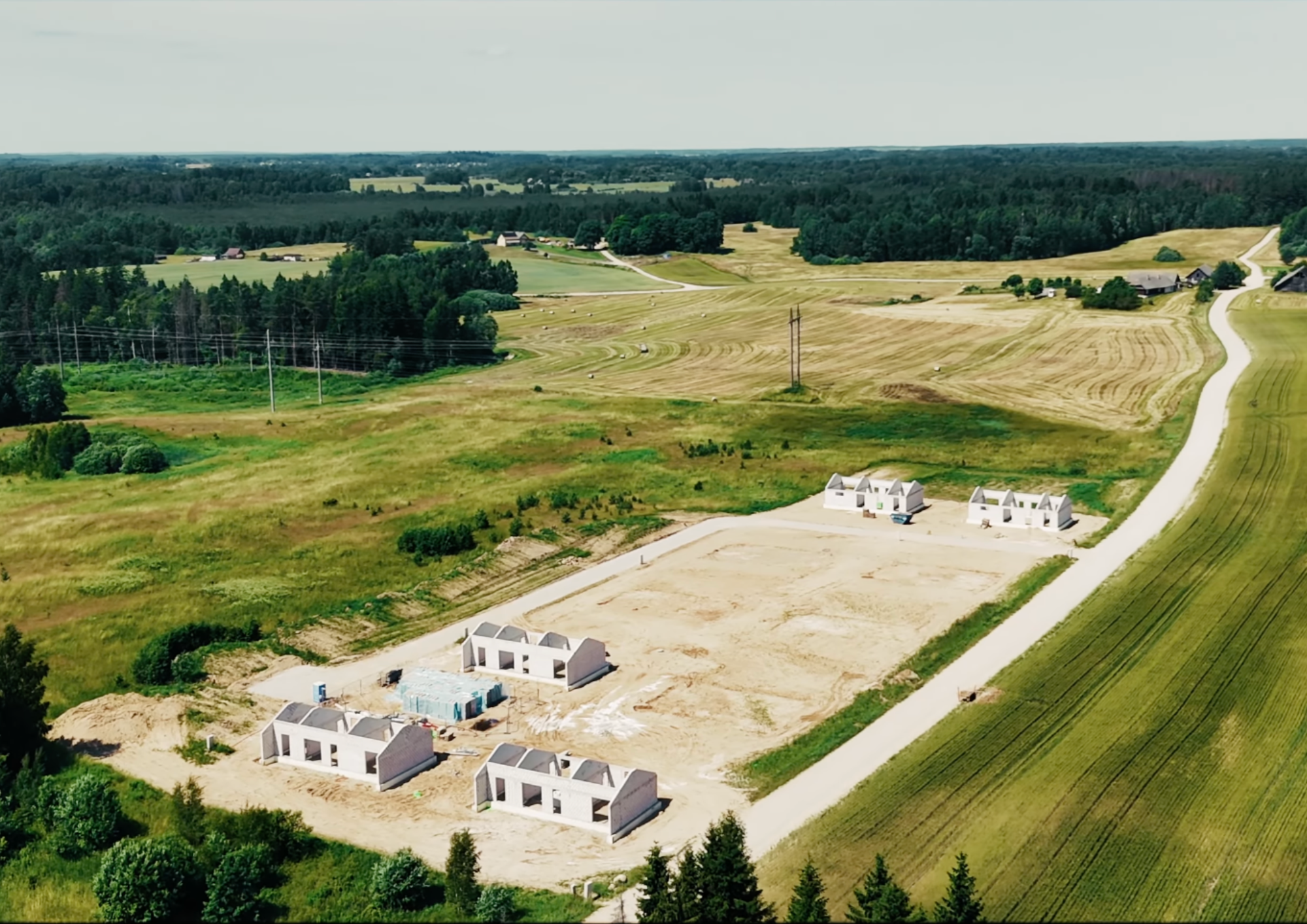 Žiedų slėnio gyvenvietės statybų eiga iš paukščio skrydžio – iškilusios pirmųjų vieno aukšto namų sienos gamtos apsuptyje netoli Vilniaus.